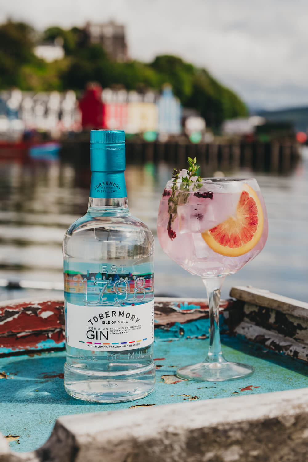 Bouteille de gin Tobermory avec verre de cocktail à base de gin dans le port de l'île de Mull